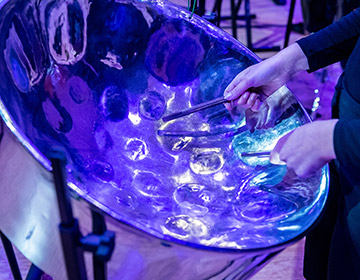 A close up on hands playing a steel drum in dramatic stage lighting