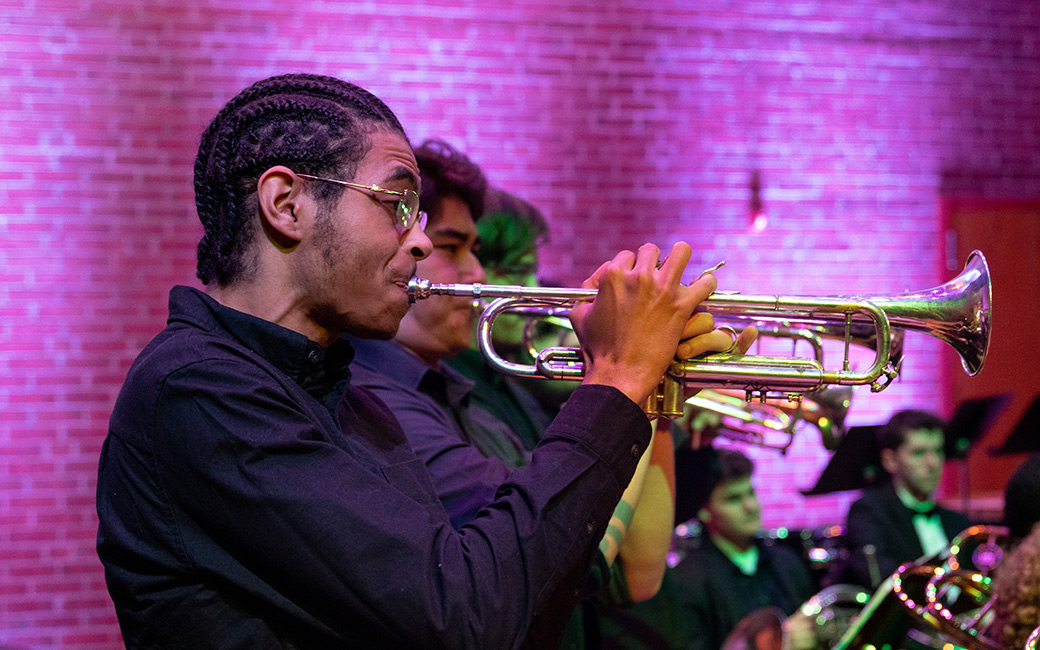 A trumpeter plays passionately under colorful theatrical lighting