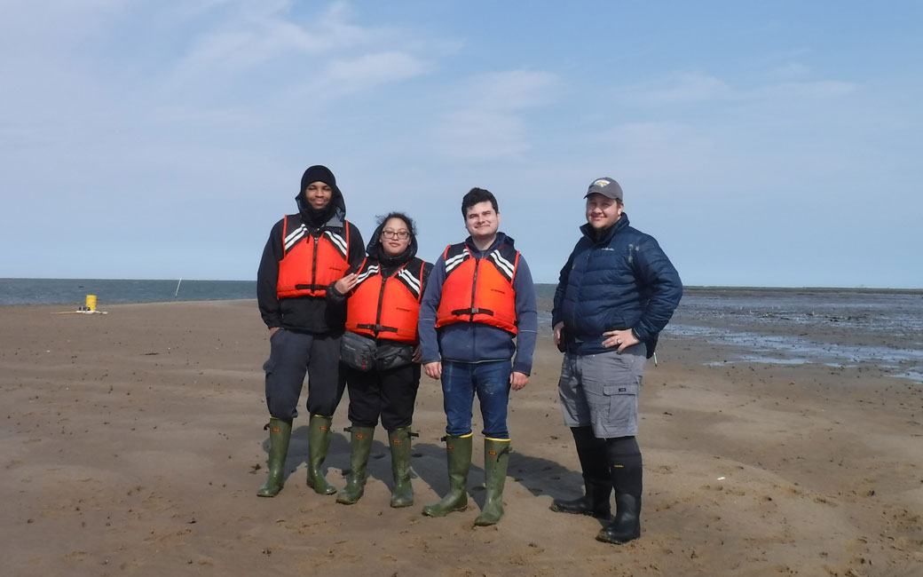 Students and professor stand on beach in Wachapreague, Virginia