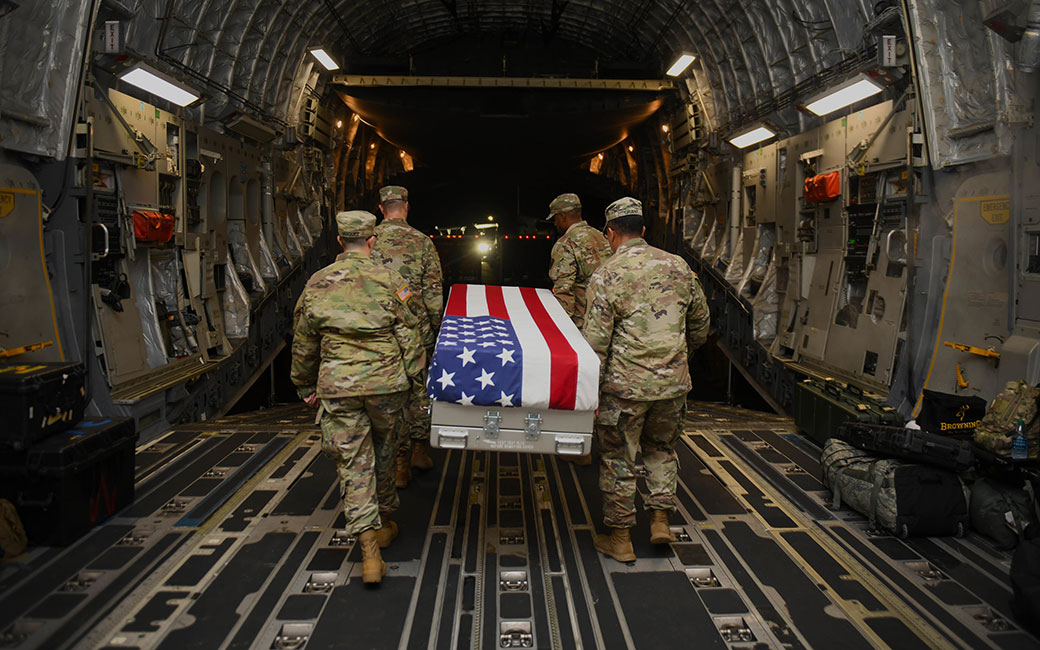 Soldiers carrying flag draped casket out of plane