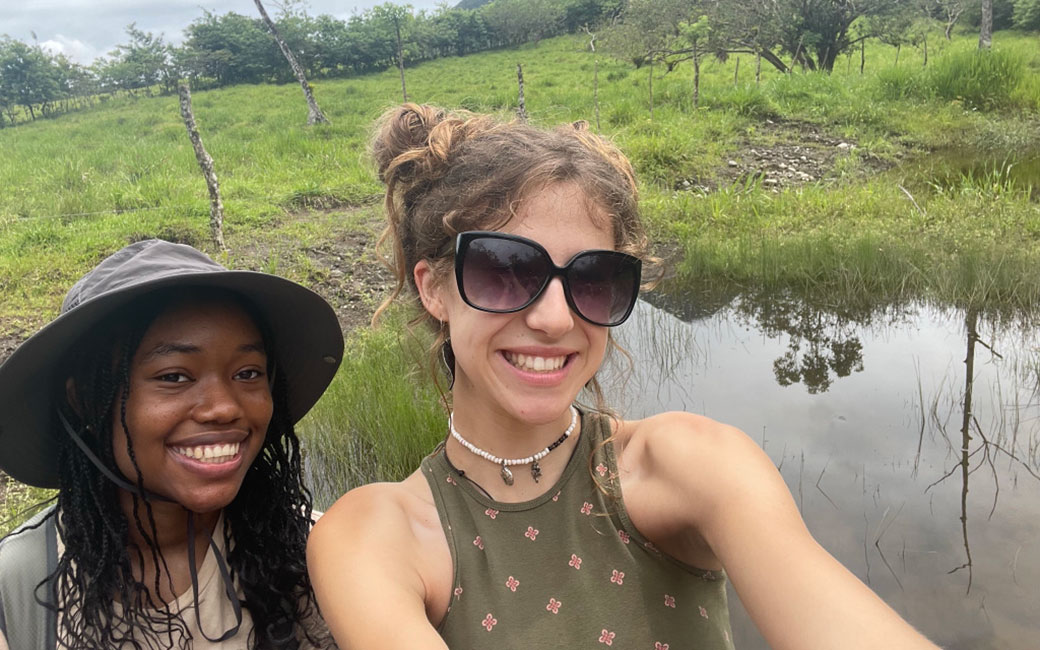 Brianna Hutchins and Caroline Etherton pose for a selfie in front of a mountain in Costa Rica