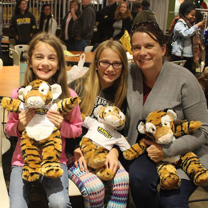 family smiling with stuffed tigers