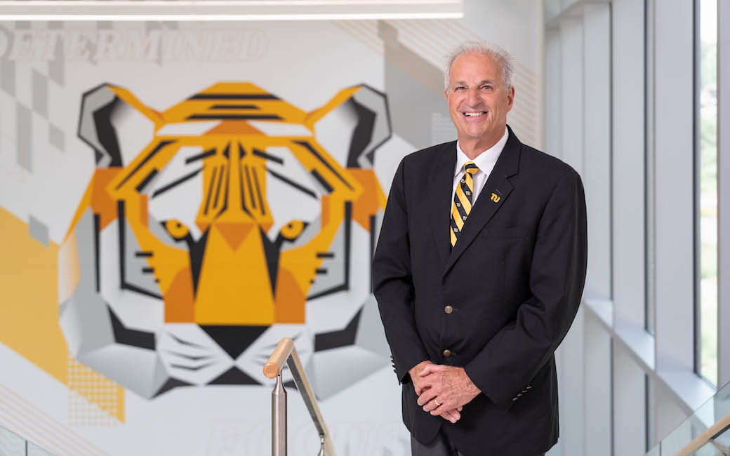 TU president Mark Ginsberg stands in front of a Towson Tiger mural