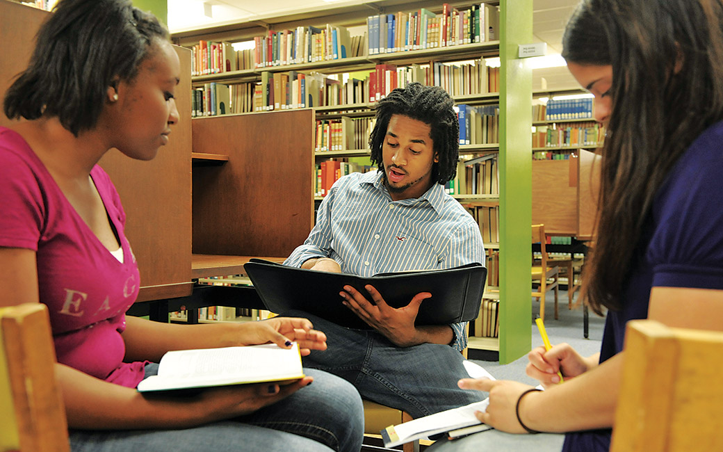 A group of three students reading together in the Towson Cook Library