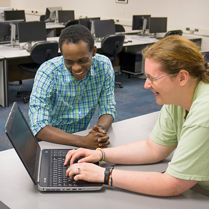 two students working on a laptop