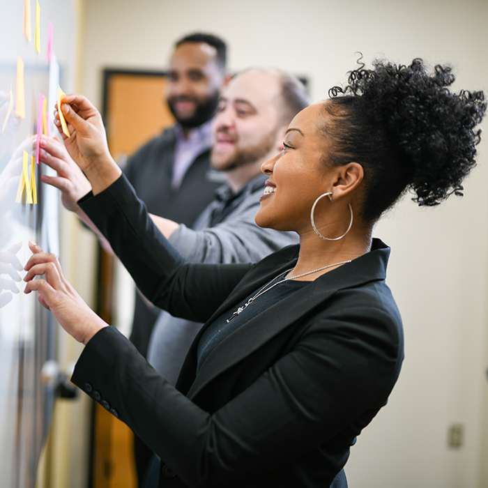 TU employees adding sticky notes to a whiteboard