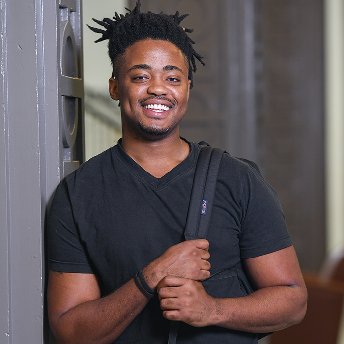 Javaunie Walters, an economics student at Towson University, stands in Stephens Hall with his backpack slung over his shoulder and smiles.