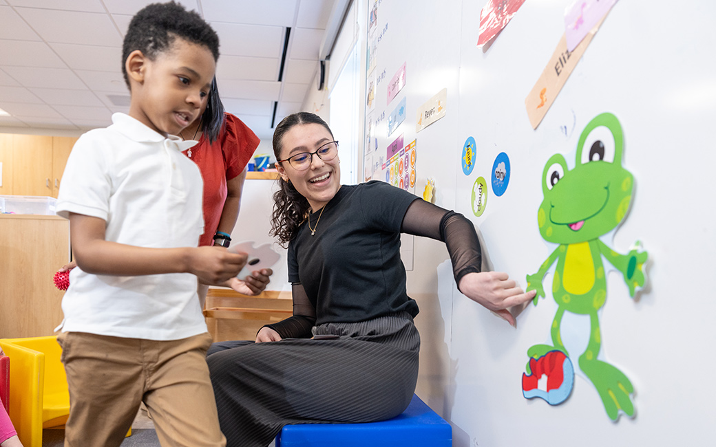 Student helps child dress cartoon frog