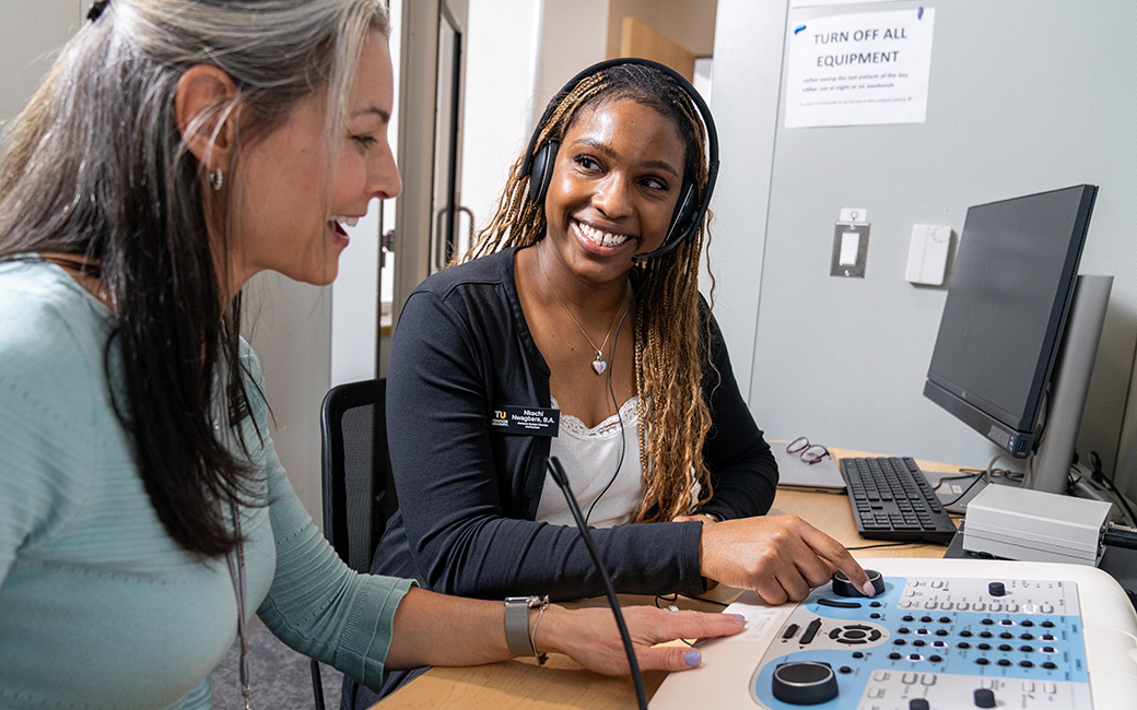 student and faculty member work in hearing booth