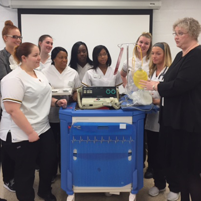 Nursing students and professor standing around a lab cart