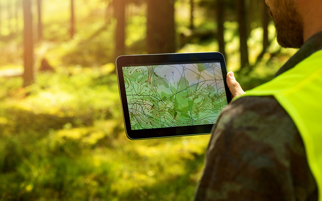 A man in the woods looking at a tablet