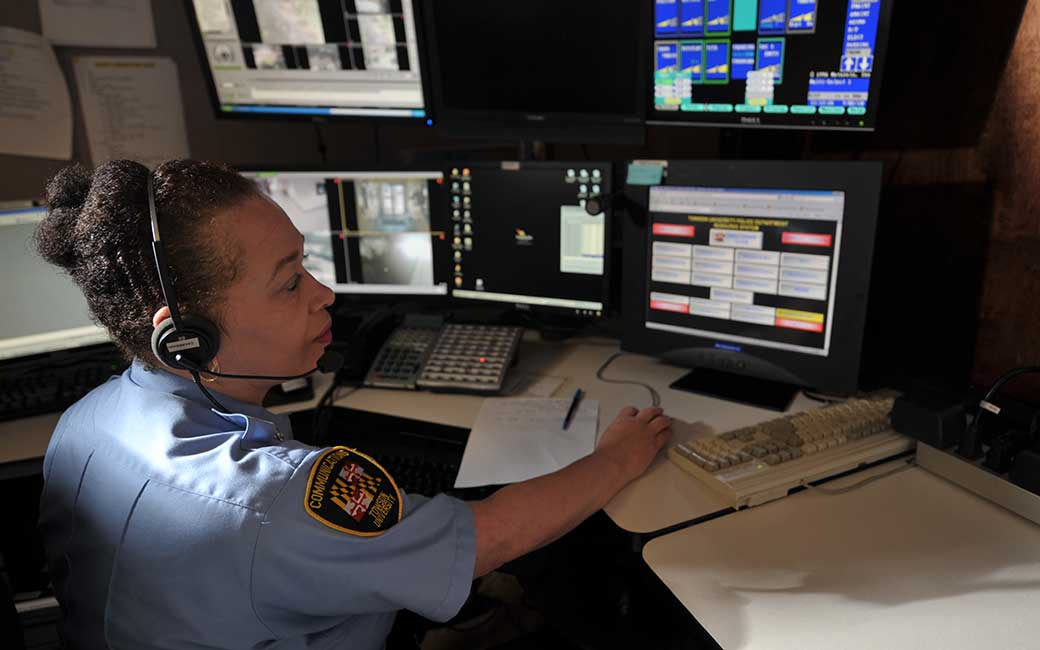 woman in uniform at desk monitoring computer screens