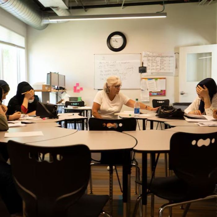 Judy Frye Jones, a volunteer English teacher at the St. Francis Neighborhood Center, has her Afghan students read aloud from lesson packets. The students work together to understand confusing words and deciding if the sentences are correct. (Taneen Momeni/The Baltimore Banner)