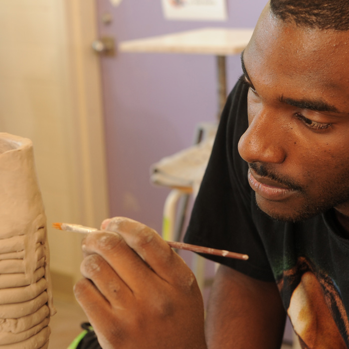 one male student working on a ceramic student