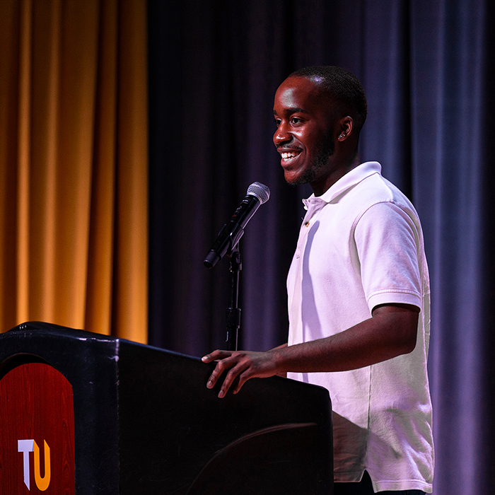 A student speaking on stage at a podium