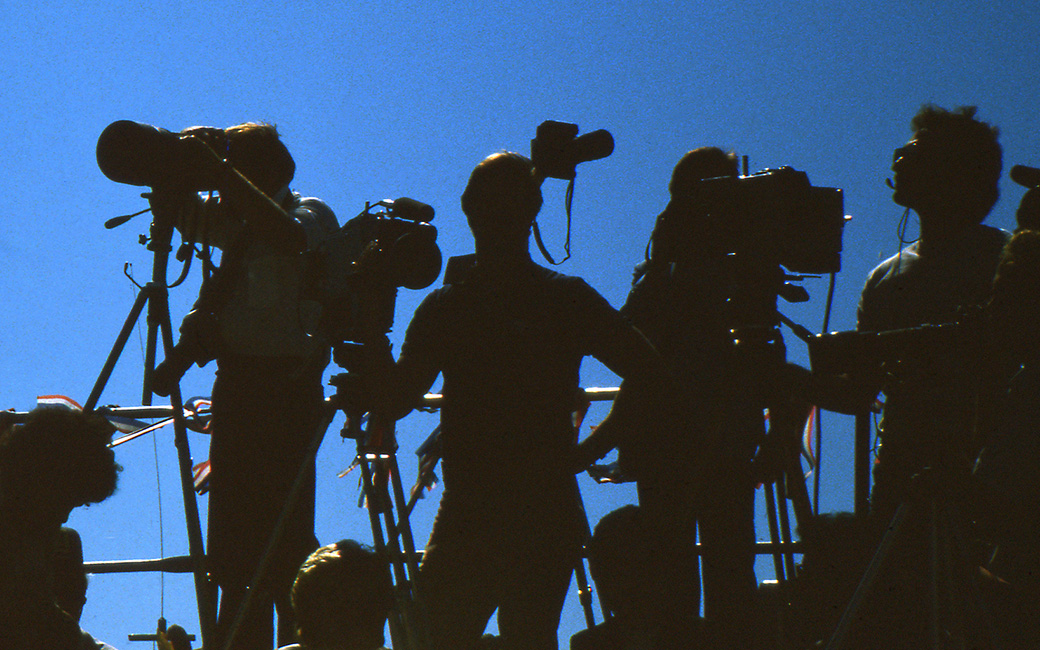 silhouetted communications professionals with video camera equipment