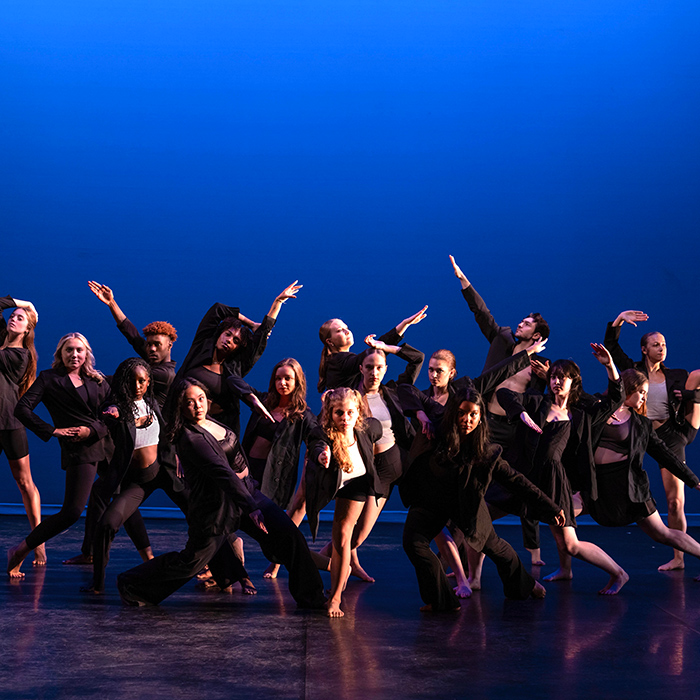 TU dancers strike dramatic poses in front of a blue background