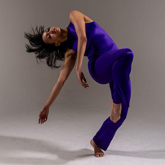 A dancer in purple in a striking pose with her head thrown back
