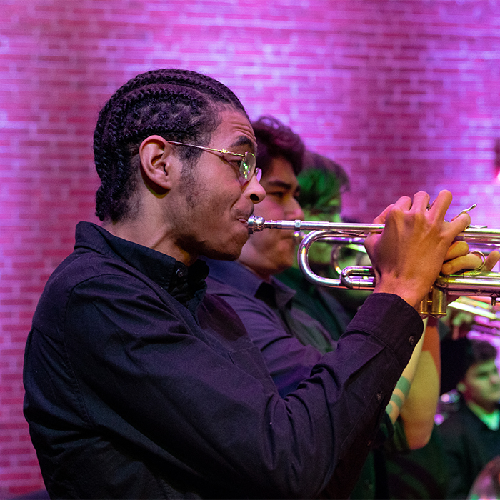 A trumpet player against a colorfully lit background