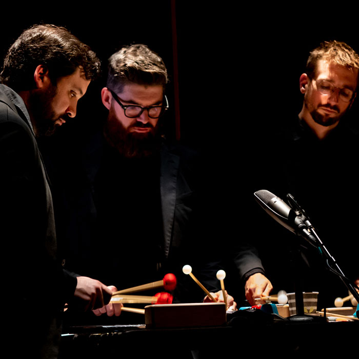 Three percussionists against a black background