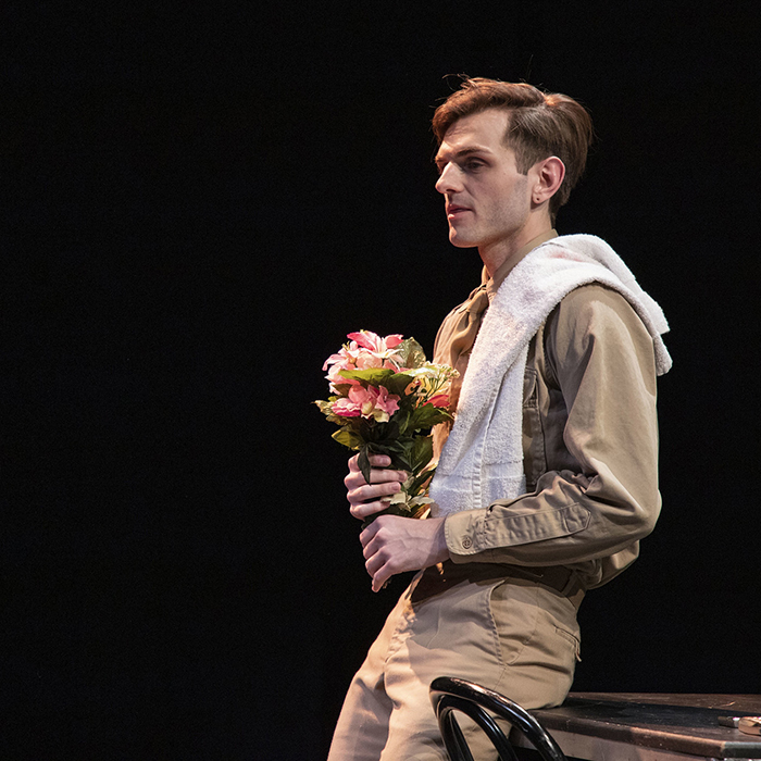 A scene from Lily, Arthur: a soldier, Mac, forlornly holds a bouquet of flowers