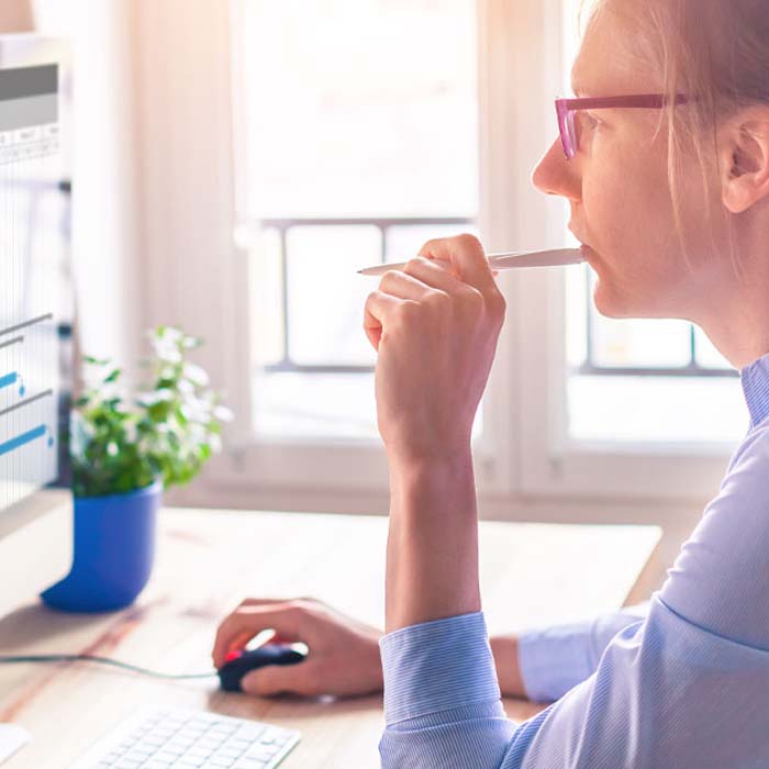 woman looking at computer screen with her right hand on her computer mouse