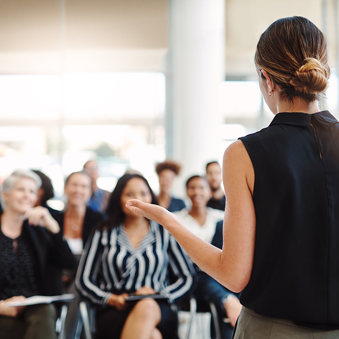 woman addressing group of people as if in a training session