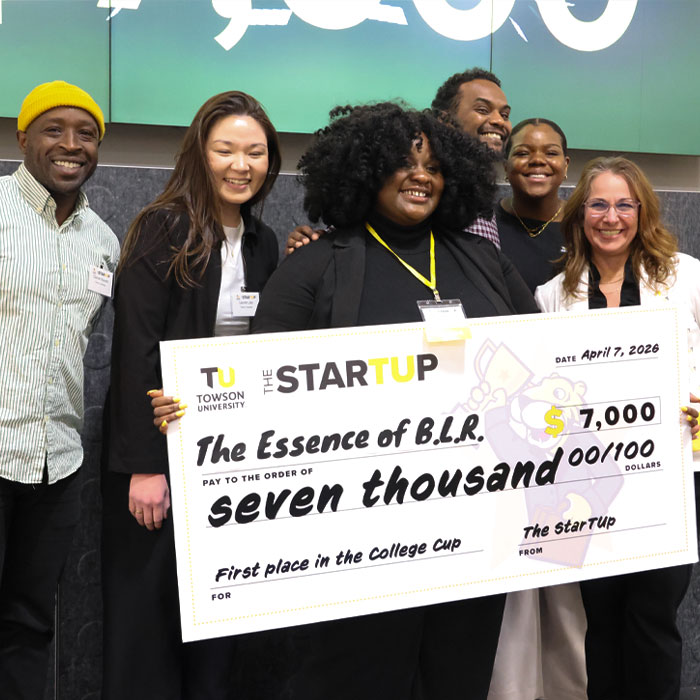 Bria Reeves, winner of 2026 college cup, holding large check with supporters