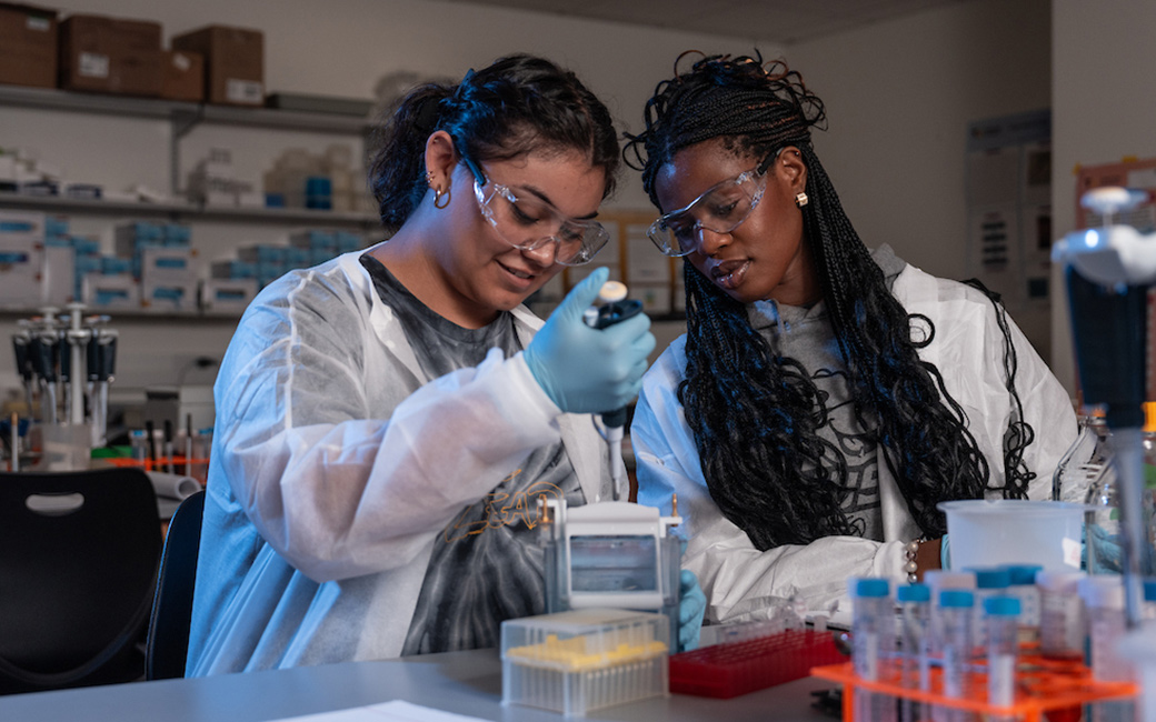 Two student performing research in a lab setting.