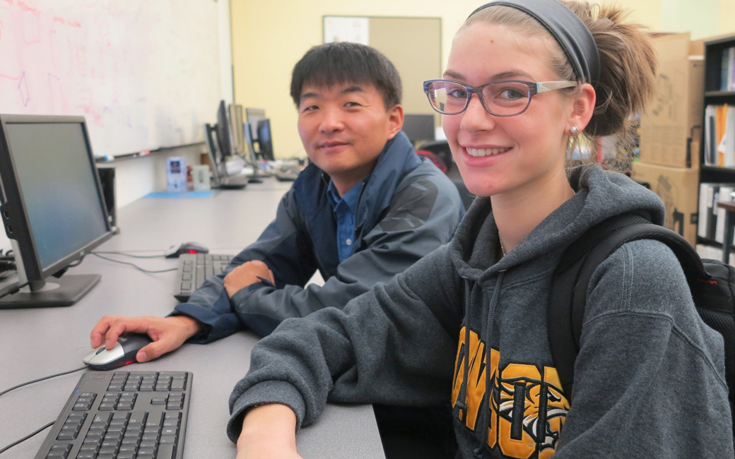 TU students sitting at a desk and in front of computers