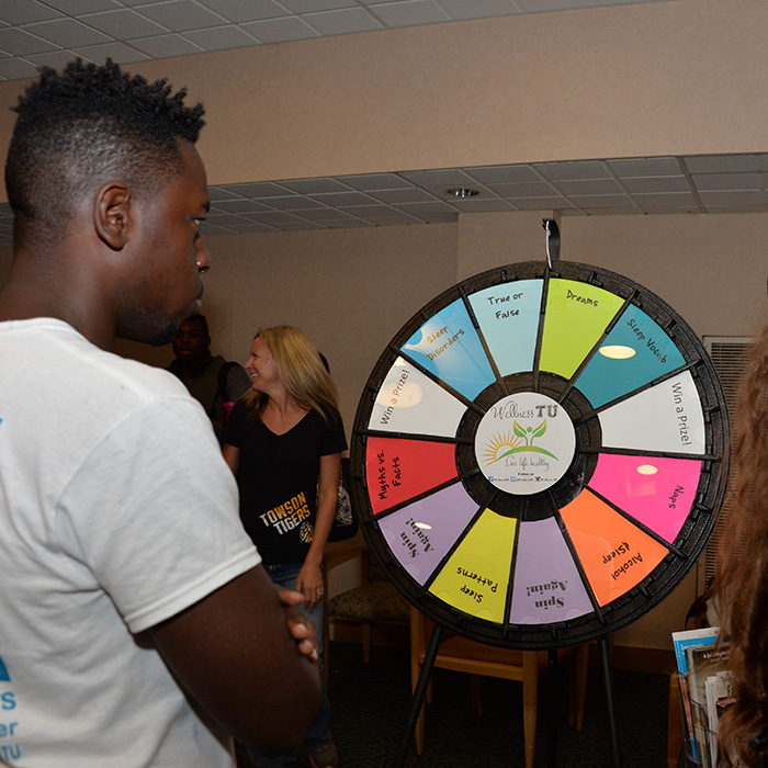 Student standing in front of trivia wheel