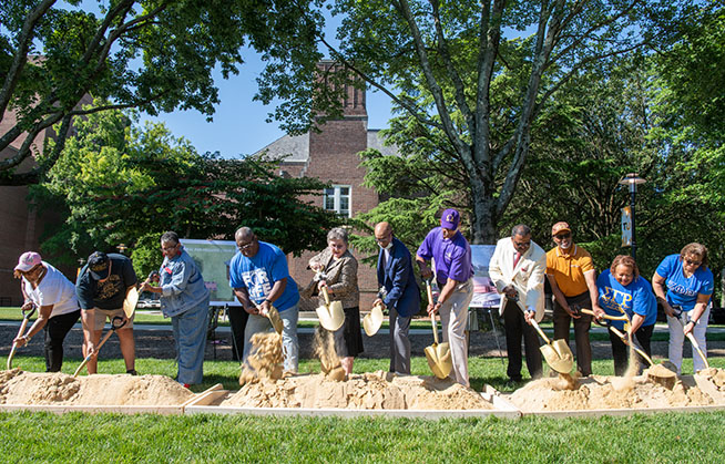 Representatives of Towson University’s historically Black fraternities and sororities join President Kim Schatzel and Dr. Julius Chapman, TU’s first dean of minority affairs, to officially launch a physical tribute to the NPHC with a ground breaking ceremony