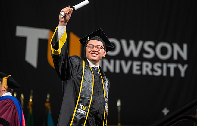 TU student holds up diploma at Commencement