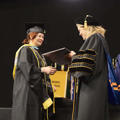 TU student in Commencement robe being presented a diploma