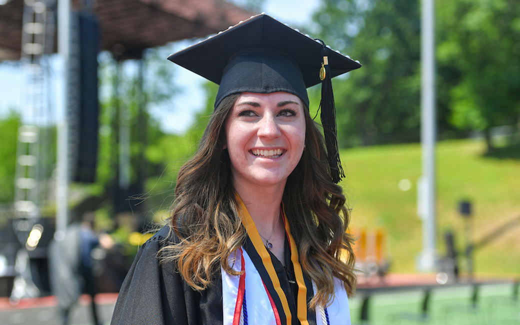 Honors student smiling while walking at commencement
