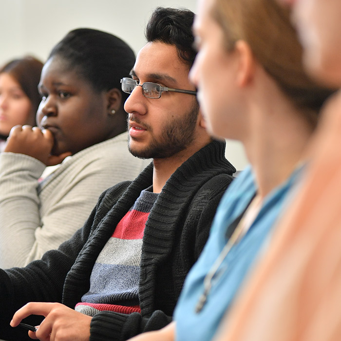 Group of students seated at table with focus on one who is speaking