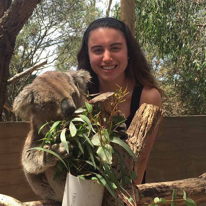 Female student standing in a forested area with a koala