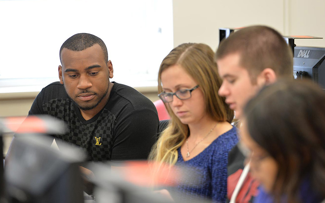 four students in front of a computer monitor