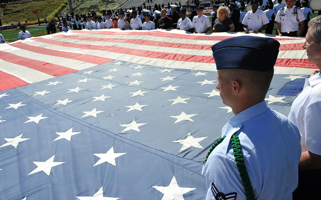 service members holding flag across field
