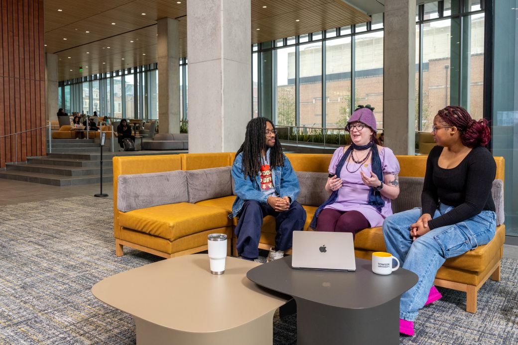 Three ADS students sitting down on a couch and talking to each other.