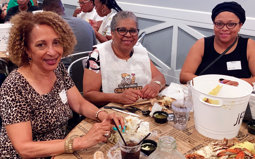 Janice Pinn, Marsha Hooker and Melanie Hooker sitting at a table picking crabs