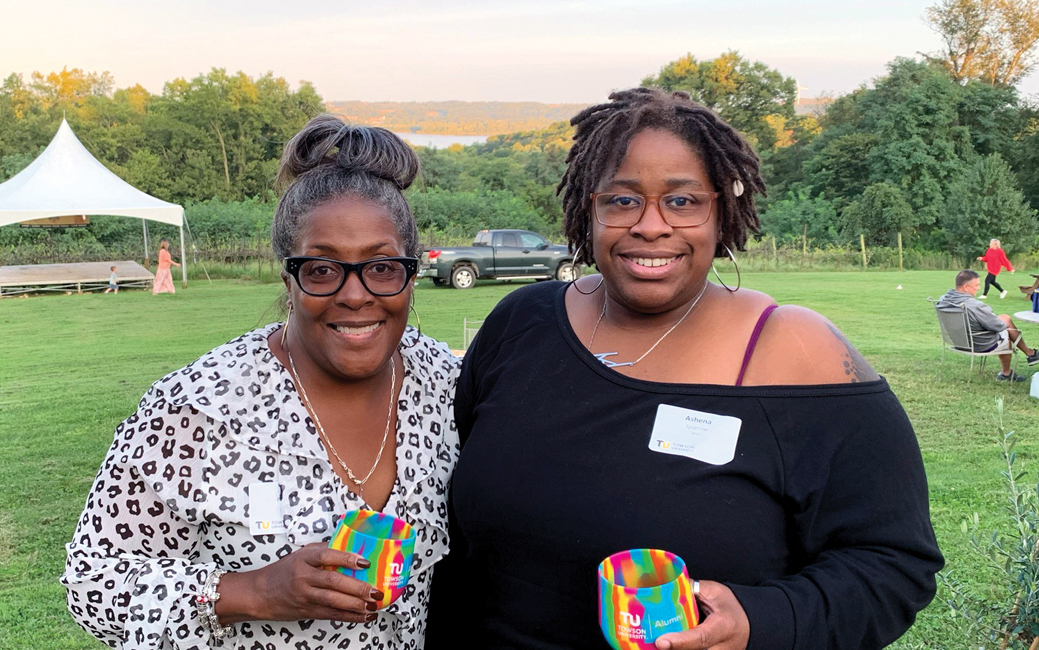 Robin Pettiford and Ashena Sparrow outside holding multicolored wine glasses