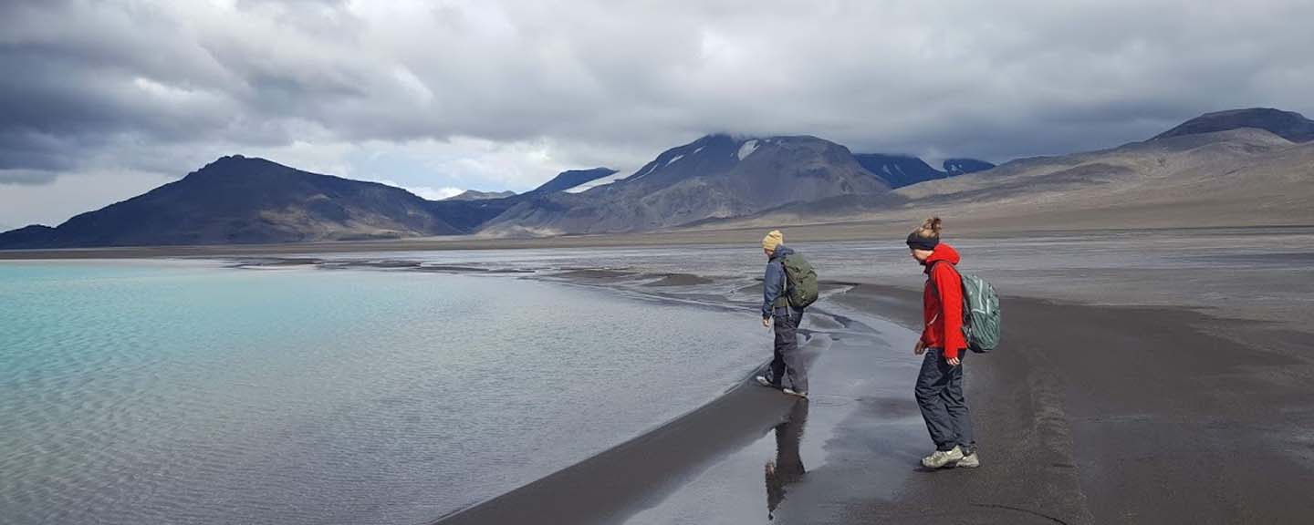 two people standing at the end of a barren lake
