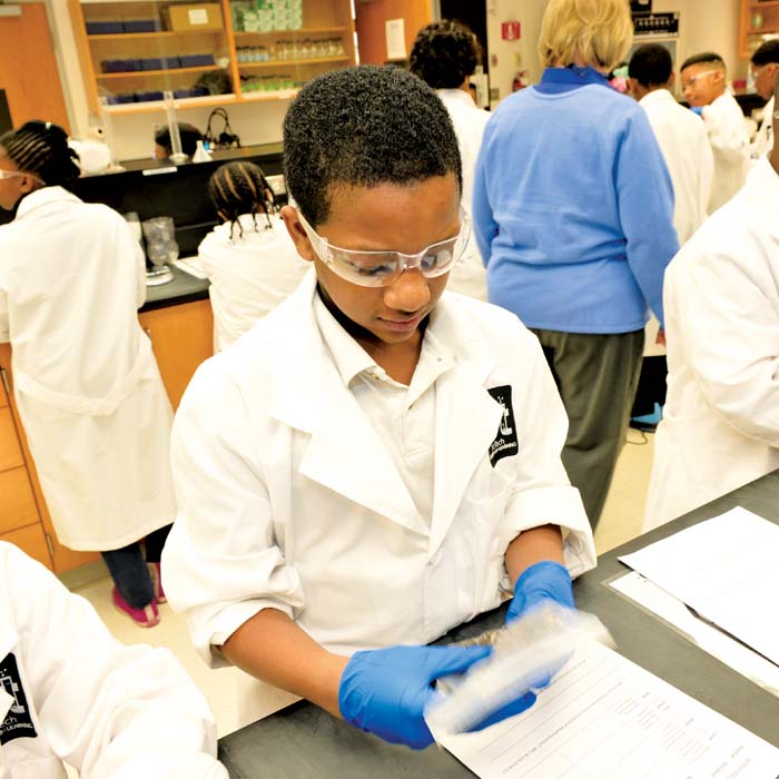 elementary student wearing goggles and a lab coat