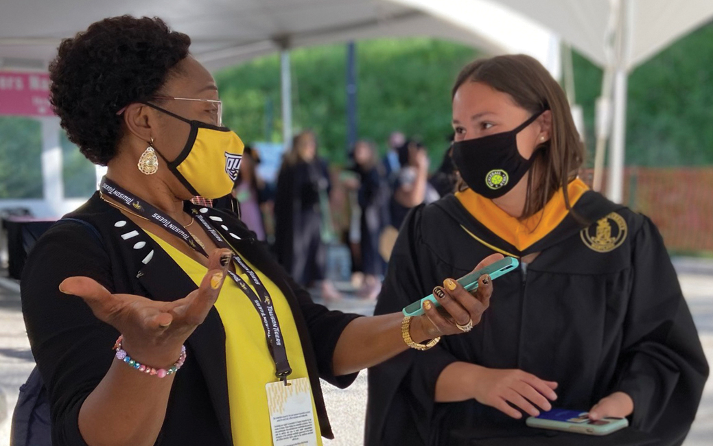 Grace Alo ’08, ’21 assists a fellow College of Health Professions graduate in the robing area.