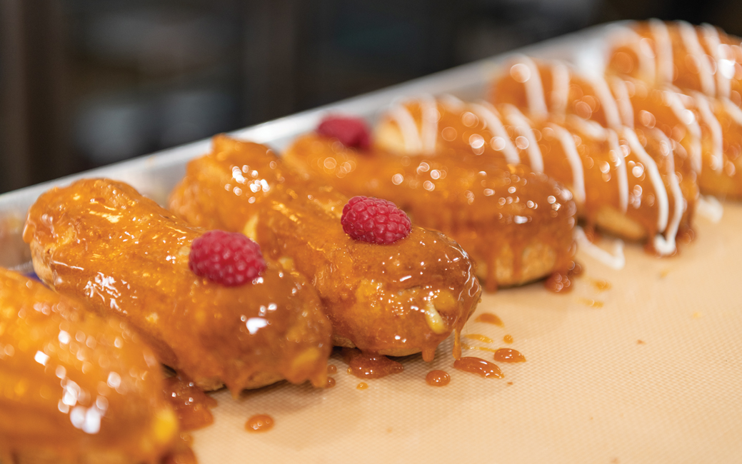 Line of glazed eclairs, some topped with raspberries