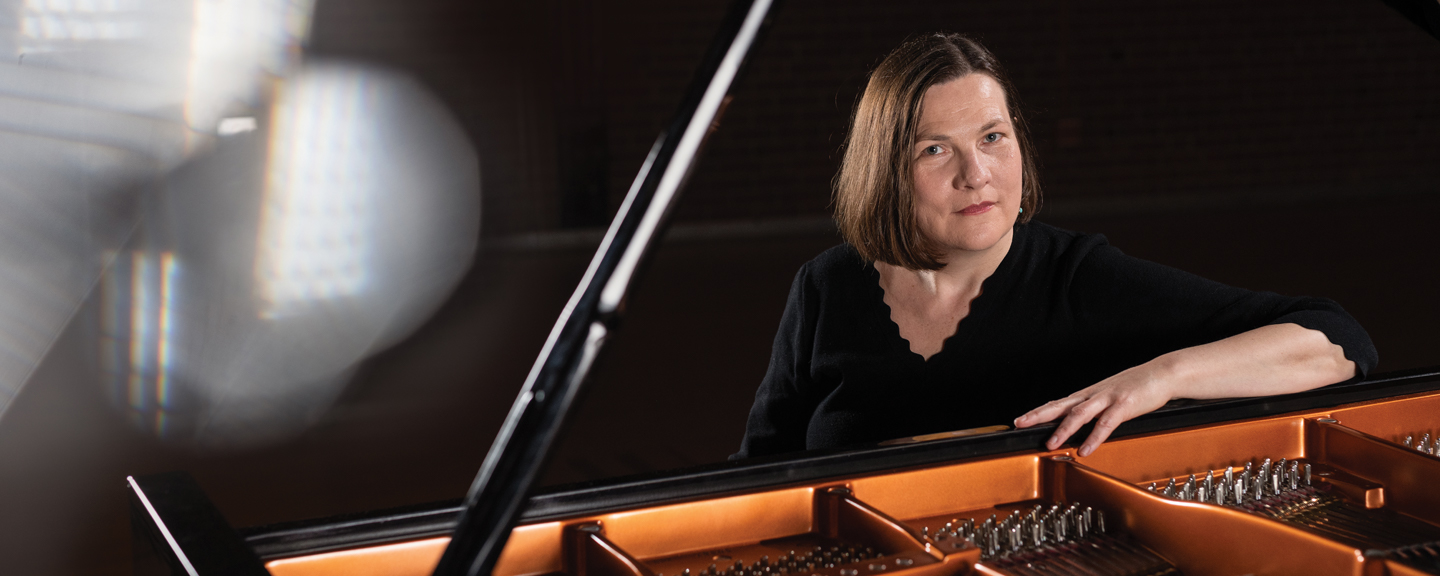 Color photo of Eva Mengelkoch sitting at a grand piano