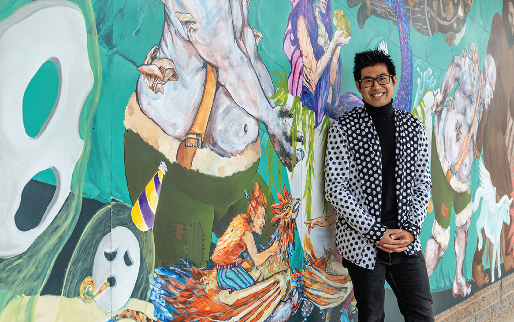 Justin Nepomuceno standing in front of his mural