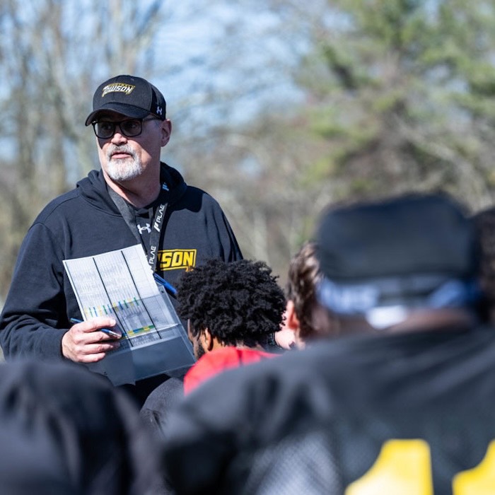 Towson University football coach Pete Shinnick meets with his team during a spring practice. 