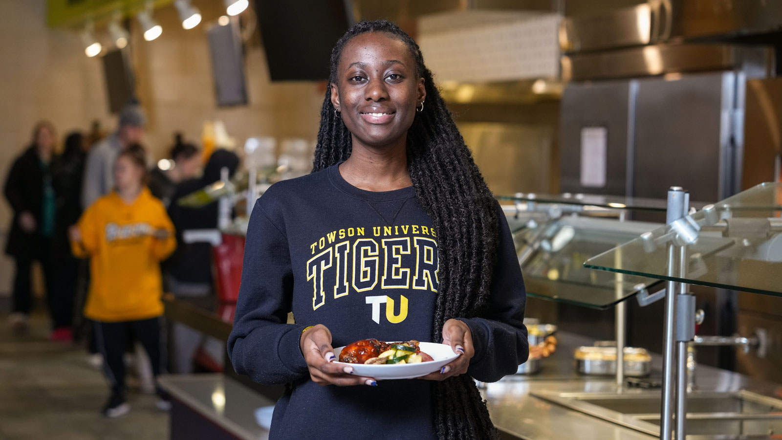 A student holding a plate at the West Village Dining Hall, one of TU's All-you-care-to-eat dining halls.